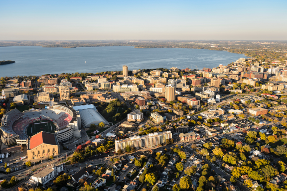 Aerial view of Madison skyline with a stadium, city buildings, and a lake in the background.