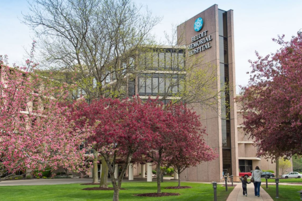 Front exterior of Beloit Memorial Hospital, with flowering trees in the foreground.